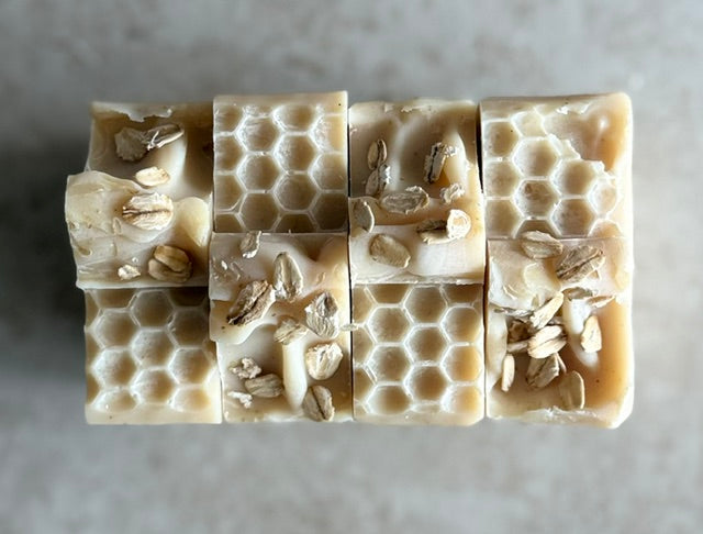 Bar of soap with honeycomb pattern and visible seeds on a neutral background